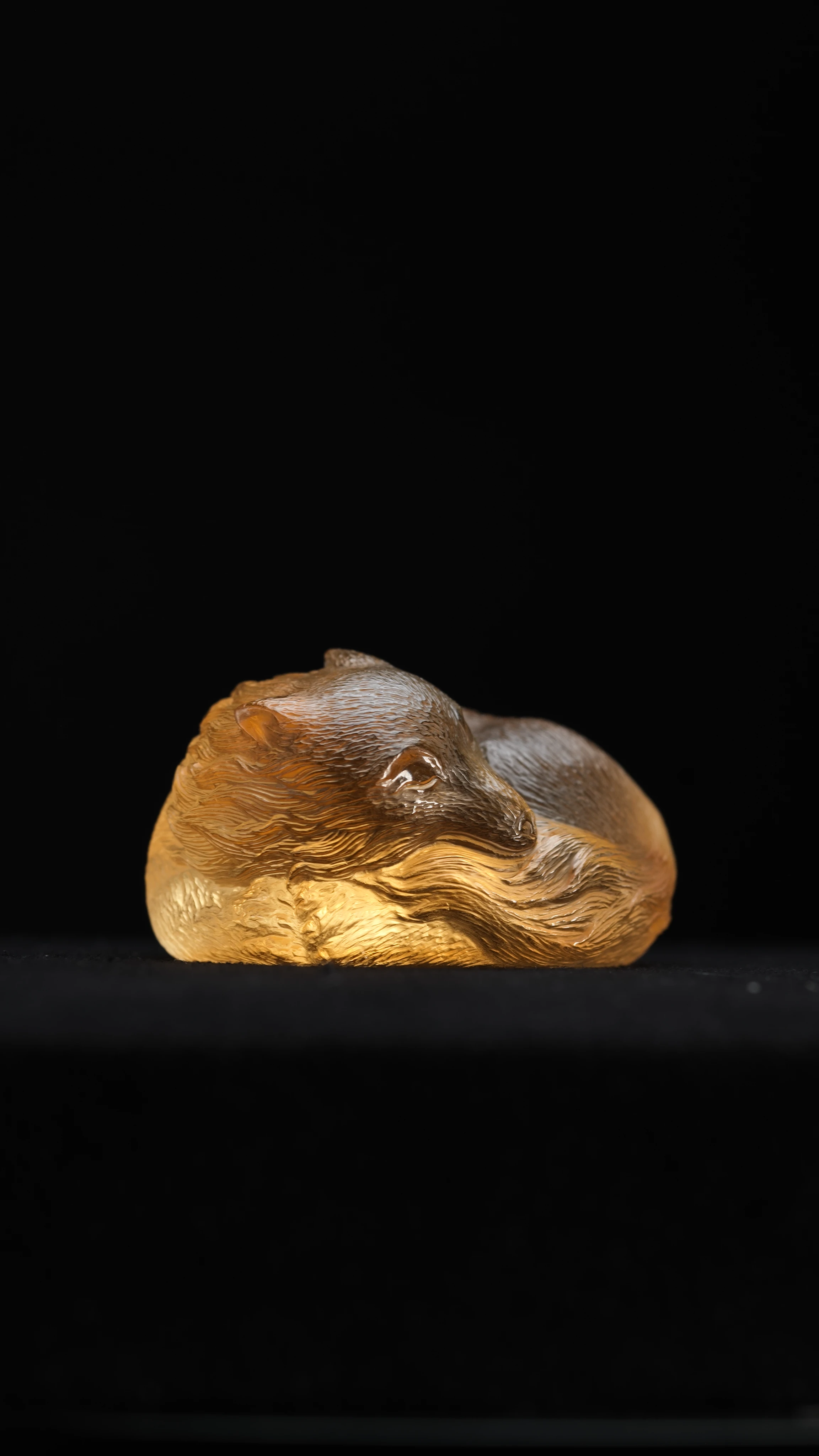 Citrine Fox, a hand carved citrine sleeping fox curled nose-to-tail, incised fur in waves following the curve of the body