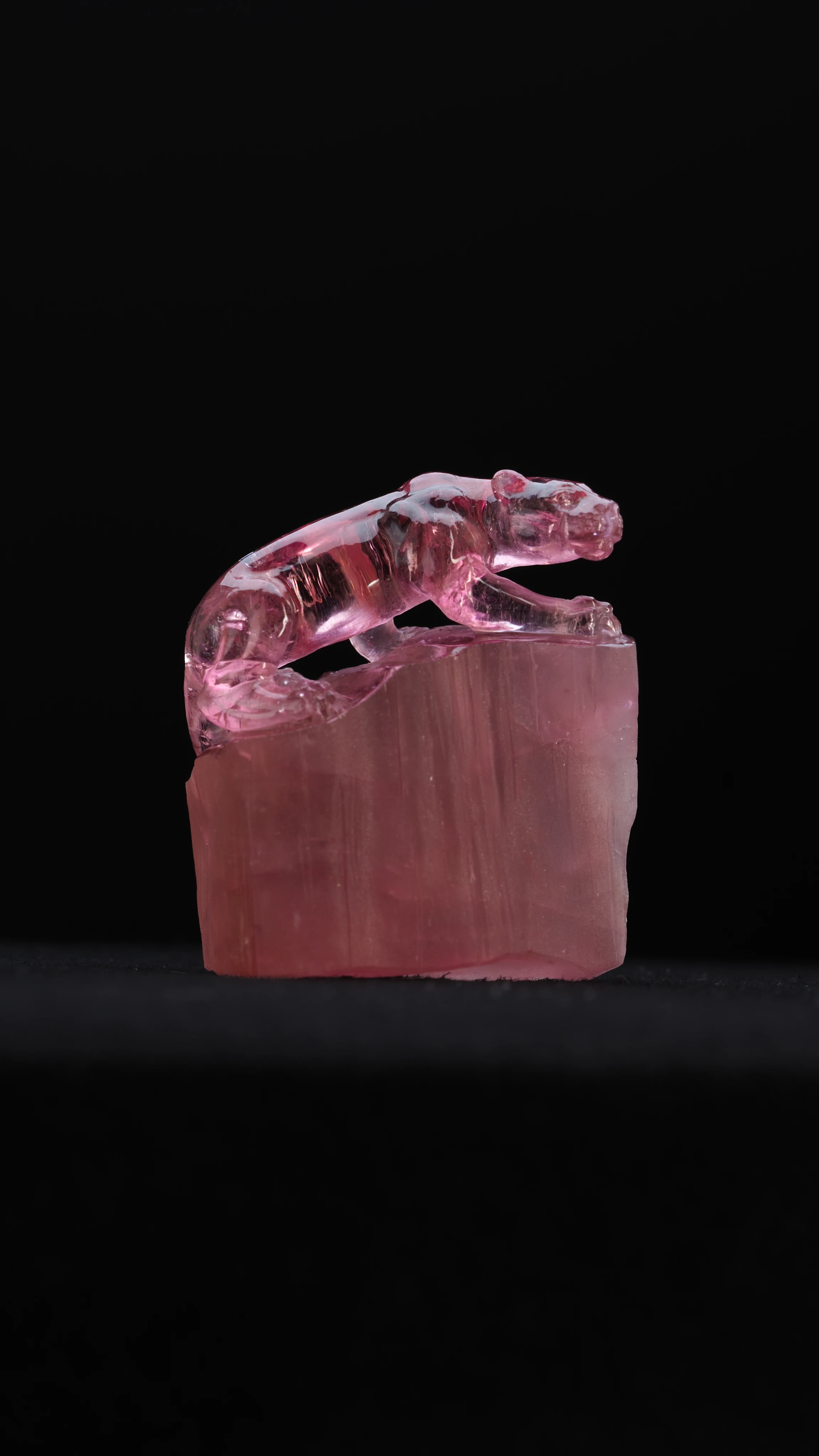 Tourmaline Leopard, a hand-carved tourmaline cat in mid-prowl standing on the unpolished base it was carved from